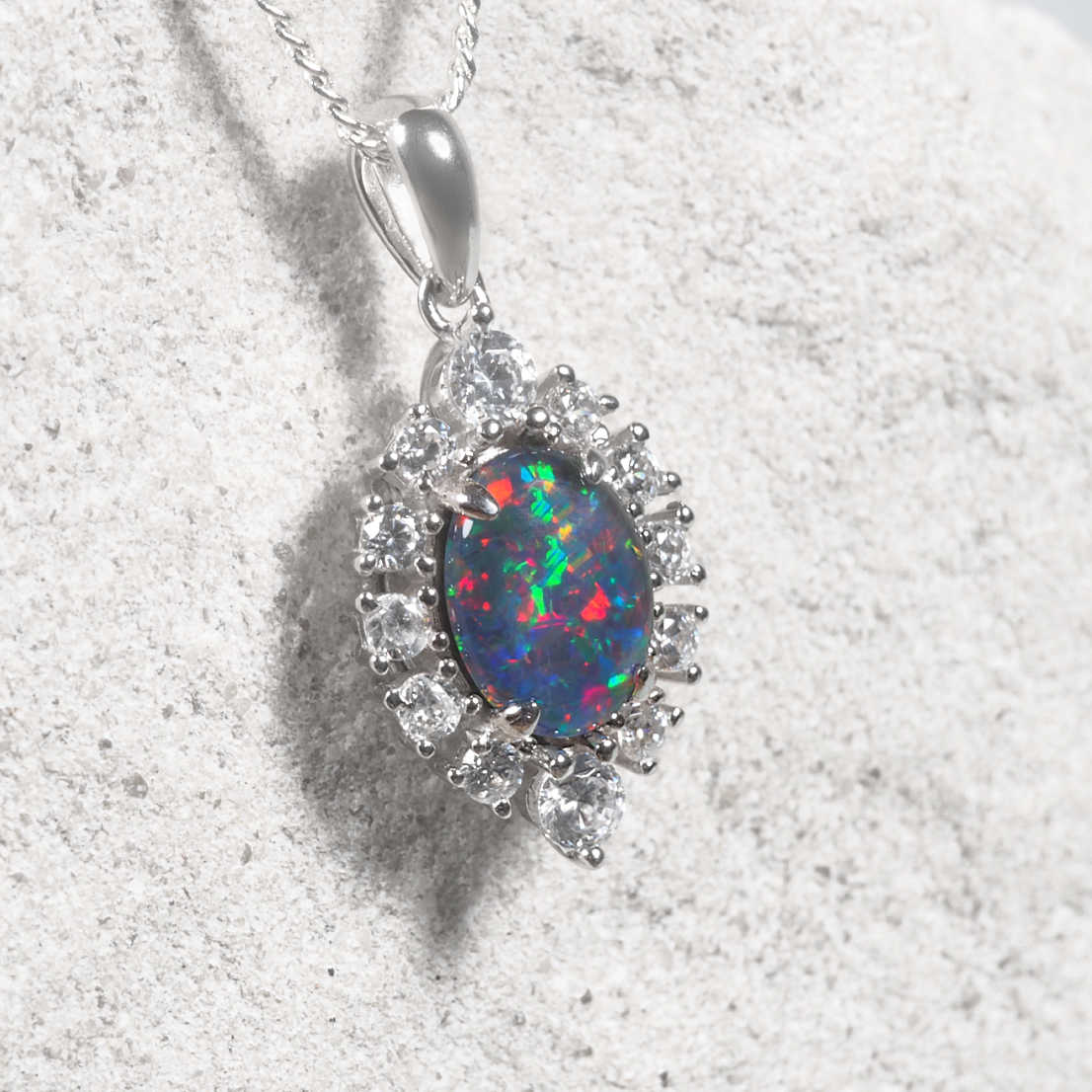 Sterling silver Australian opal necklace featuring an oval genuine opal with vibrant play-of-colour and a halo of twelve sparkling cubic zirconias.