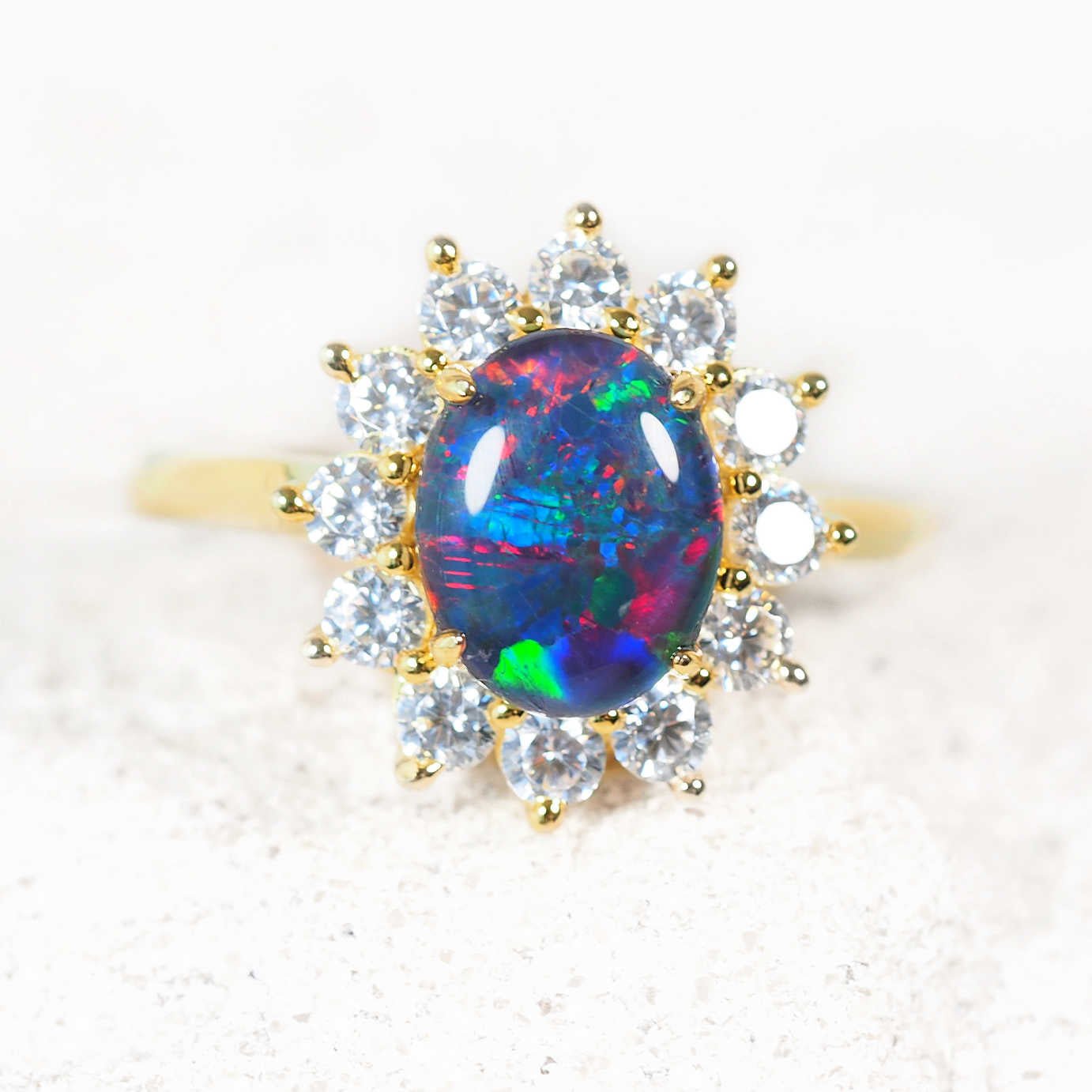 Ring with a colorful opal gemstone and diamond-like stones on a light background