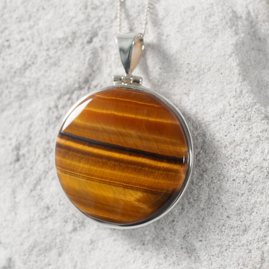 Brown Tiger’s Eye pendant featuring circular design and polished silver bezel