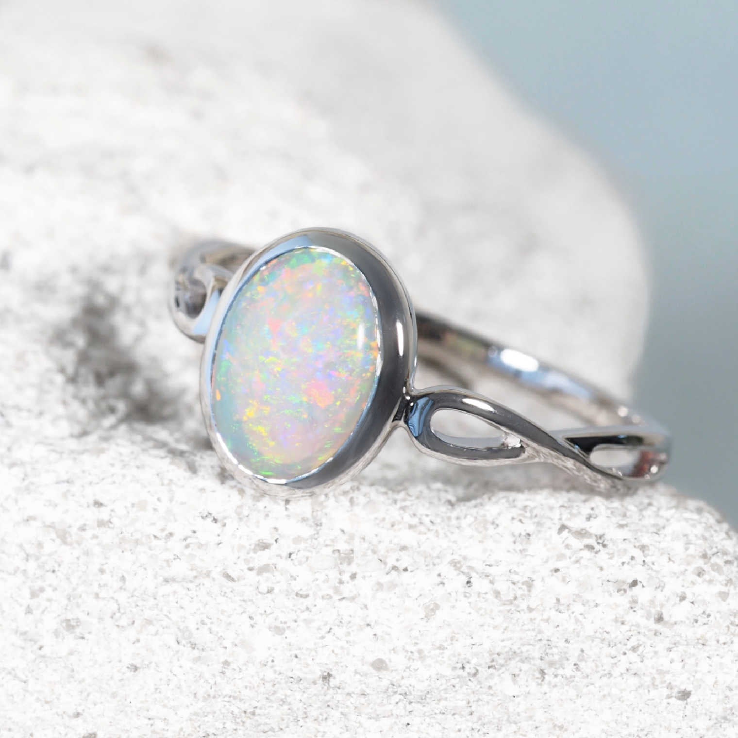 White gold opal ring with a natural opal stone on a white background