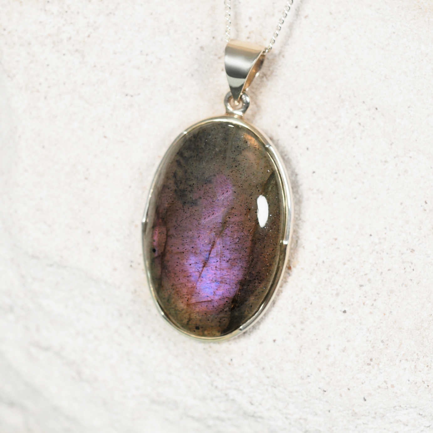 Silver pendant with a colorful gemstone on a white fabric background