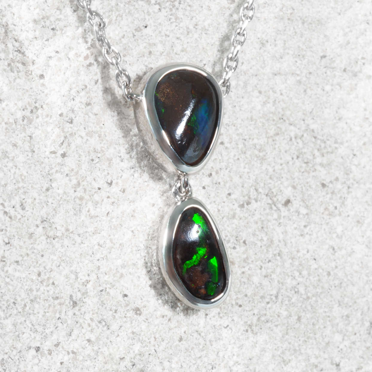 Boulder opal necklace with two opal stones on a textured white background