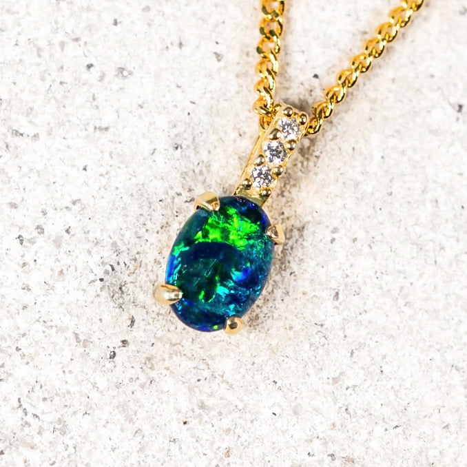 Elegant opal necklace featuring a blue-green oval triplet opal claw set in gold-plated silver with sparkling accents.