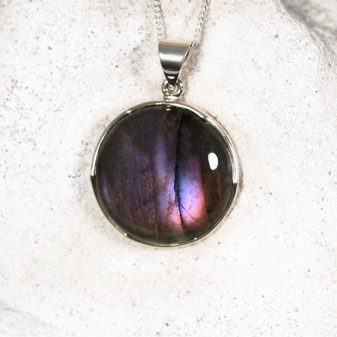 Round Labradorite pendant necklace on a white textured background