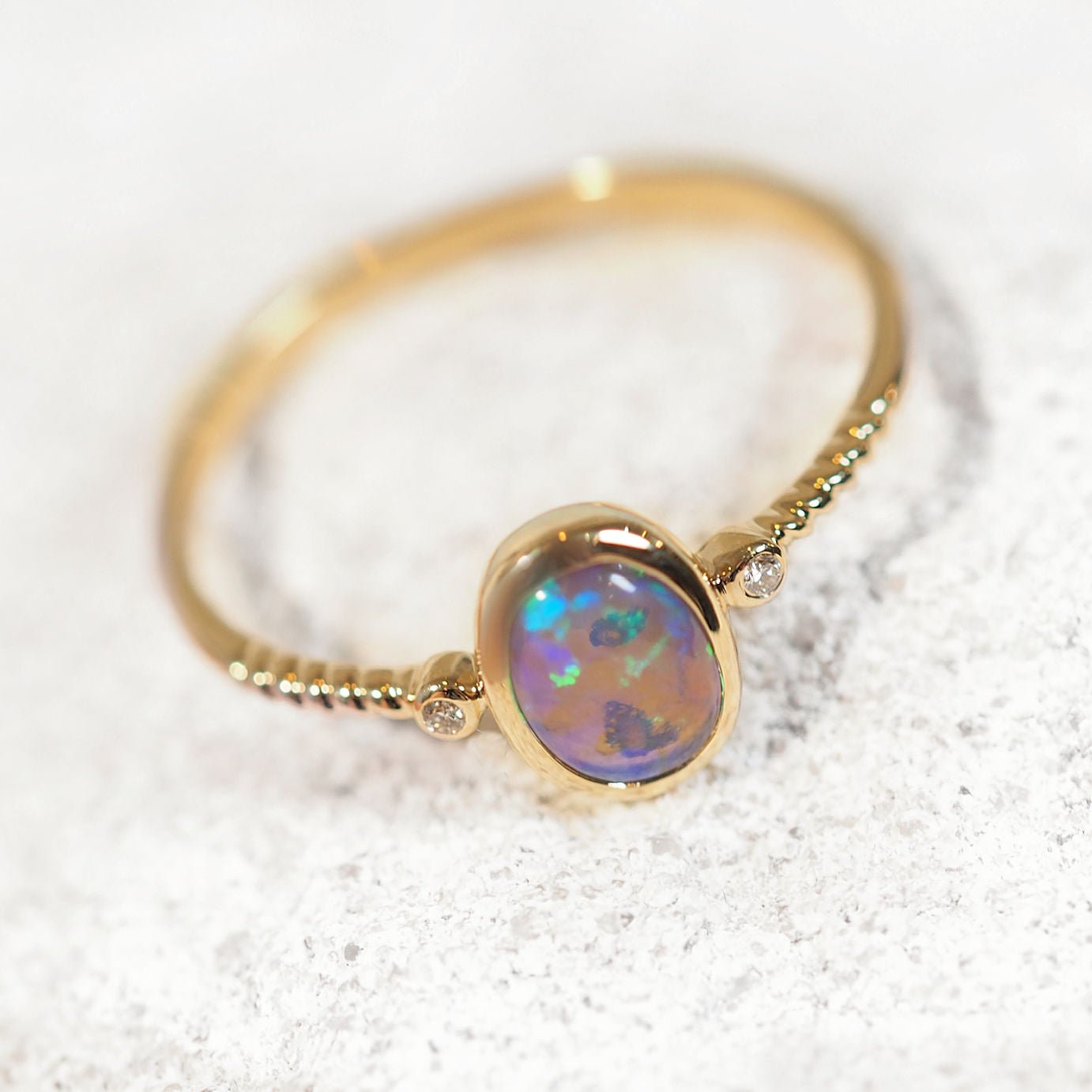 Gold ring with a colorful opal gemstone on a light background