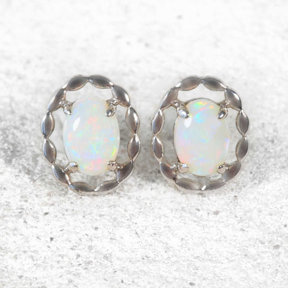 Close-up of ‘Harley’ opal earrings showcasing vibrant play-of-colour in sterling silver claw-set design.