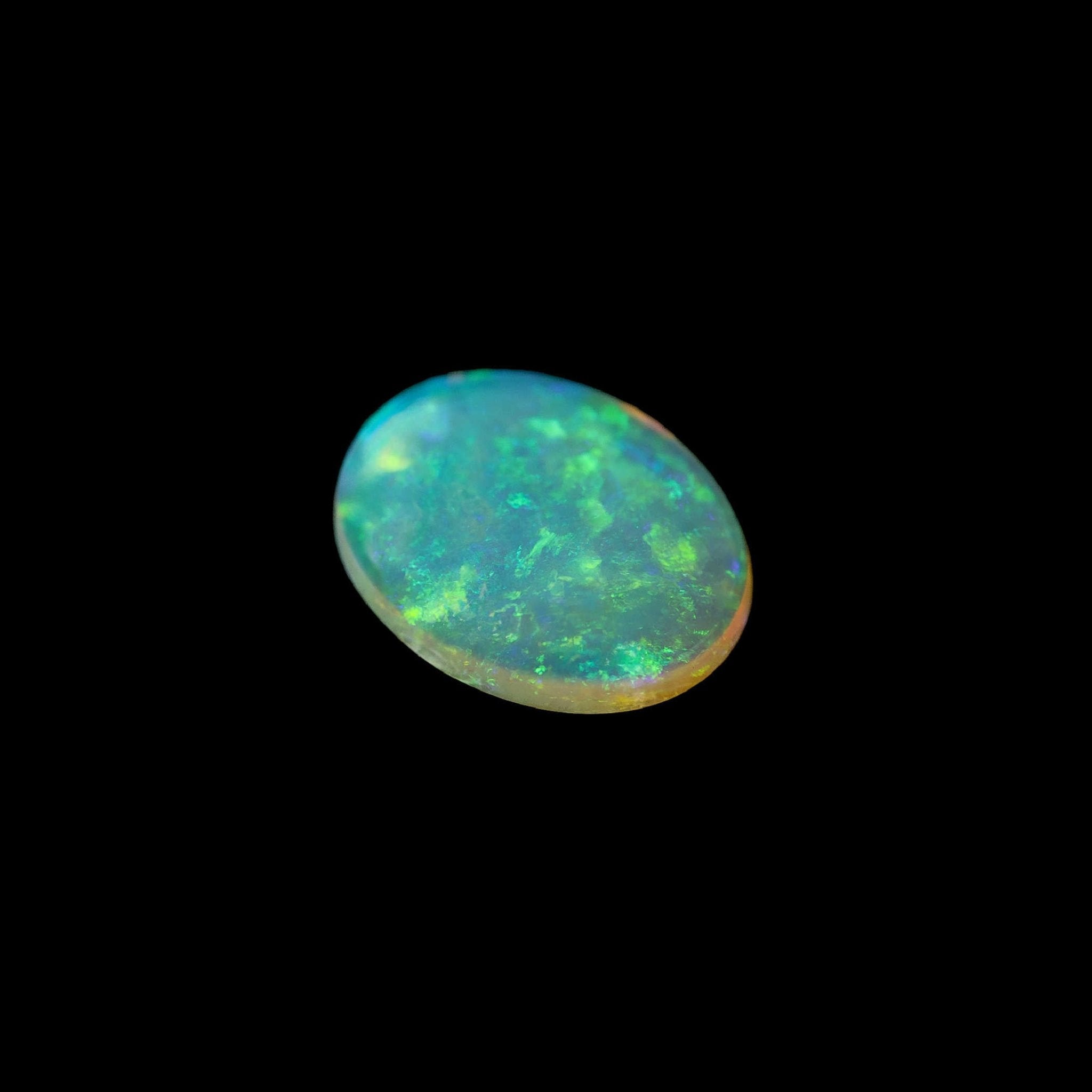 Polished oval Coober Pedy opal with luminous green and gold tones
