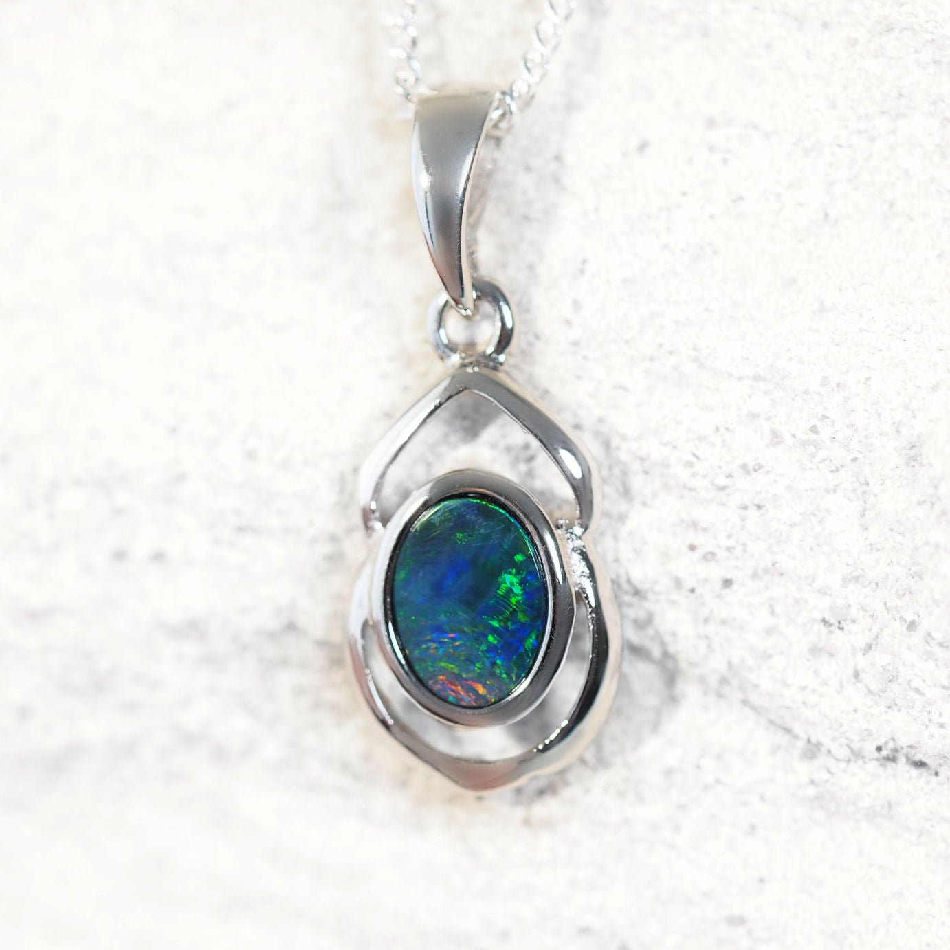 Silver opal pendant with a colorful Australian gemstone on a white background