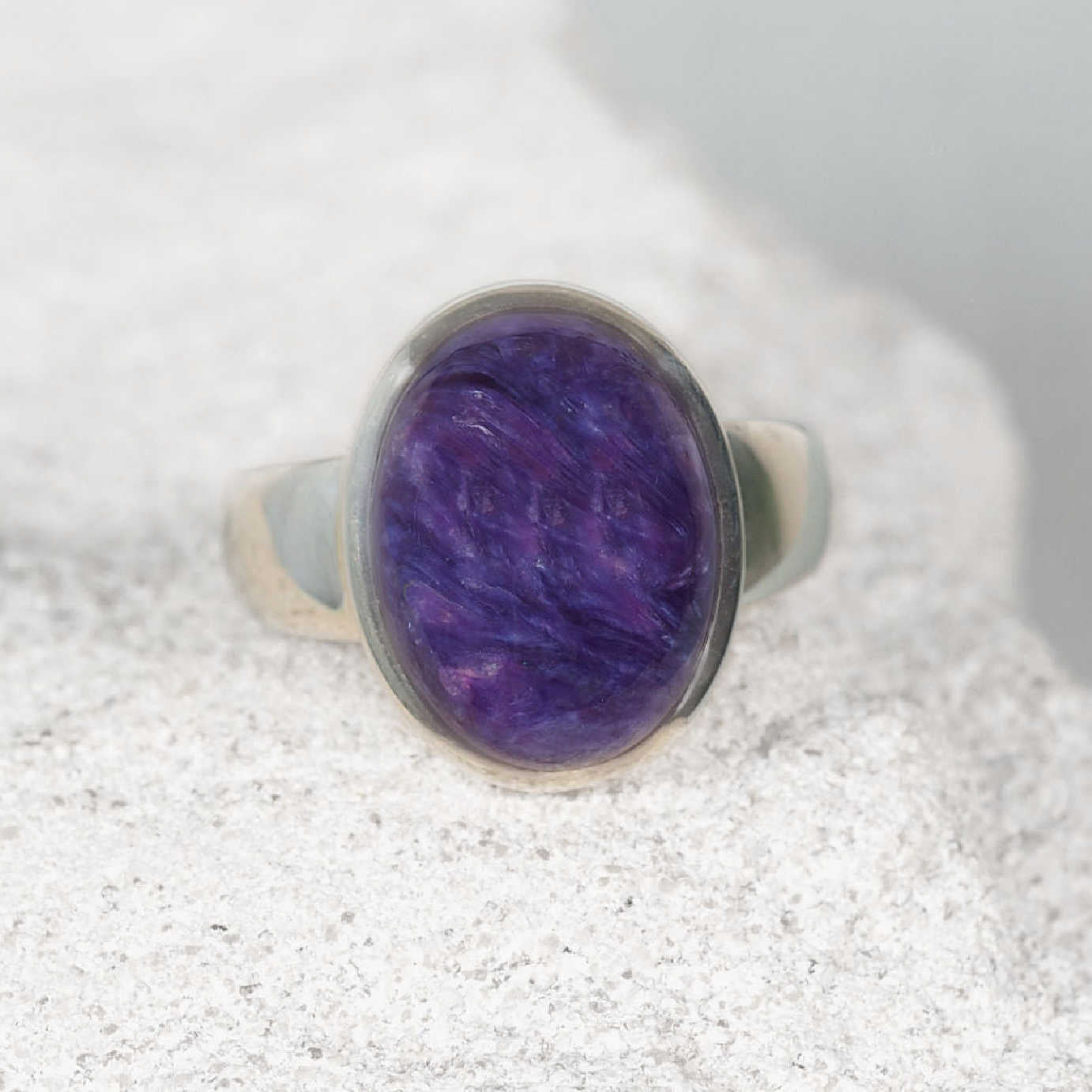 ‘Irene’ Charoite ring with a small round purple gemstone featuring soft lavender and white swirls, set in polished silver.