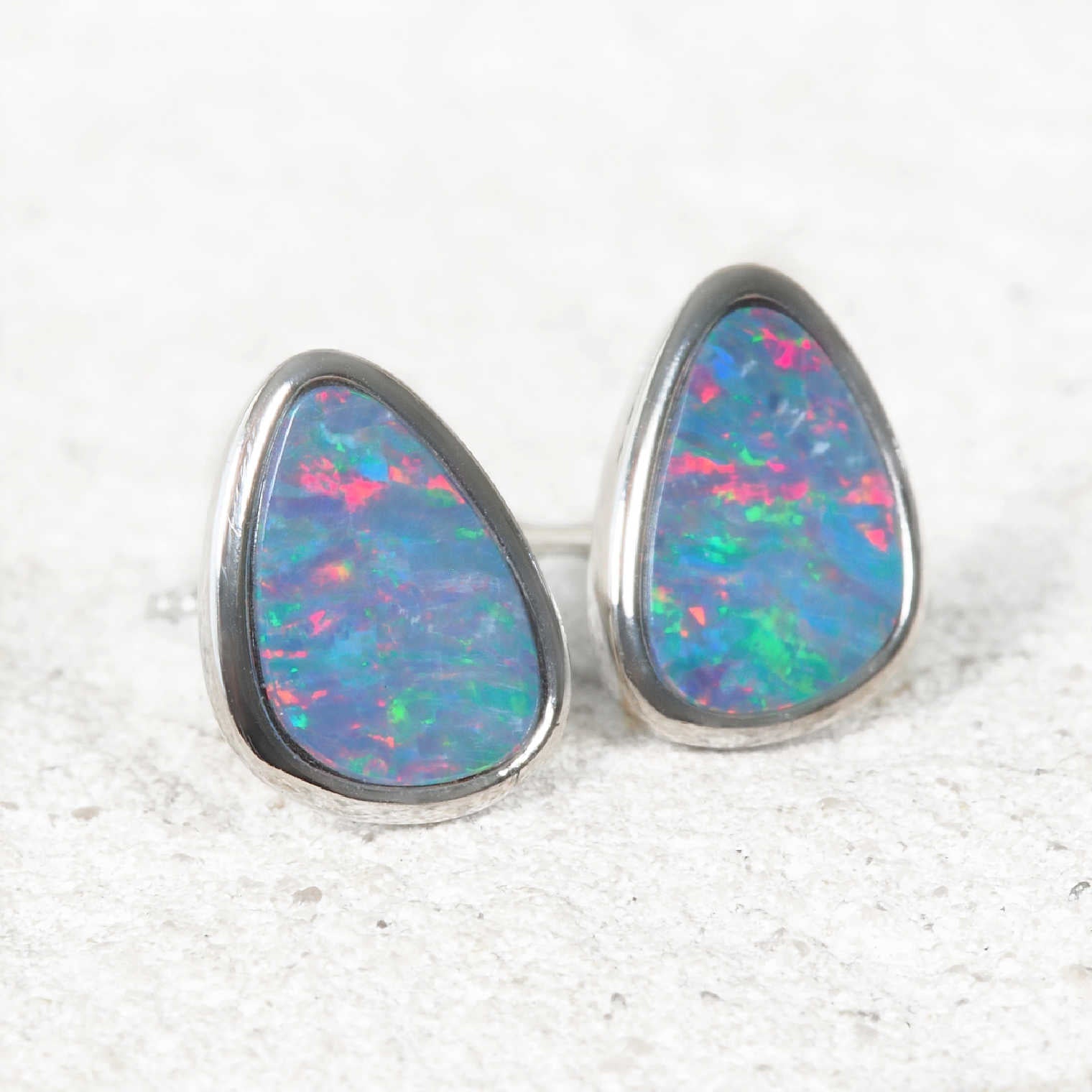 Opal earrings with silver setting on a textured white background