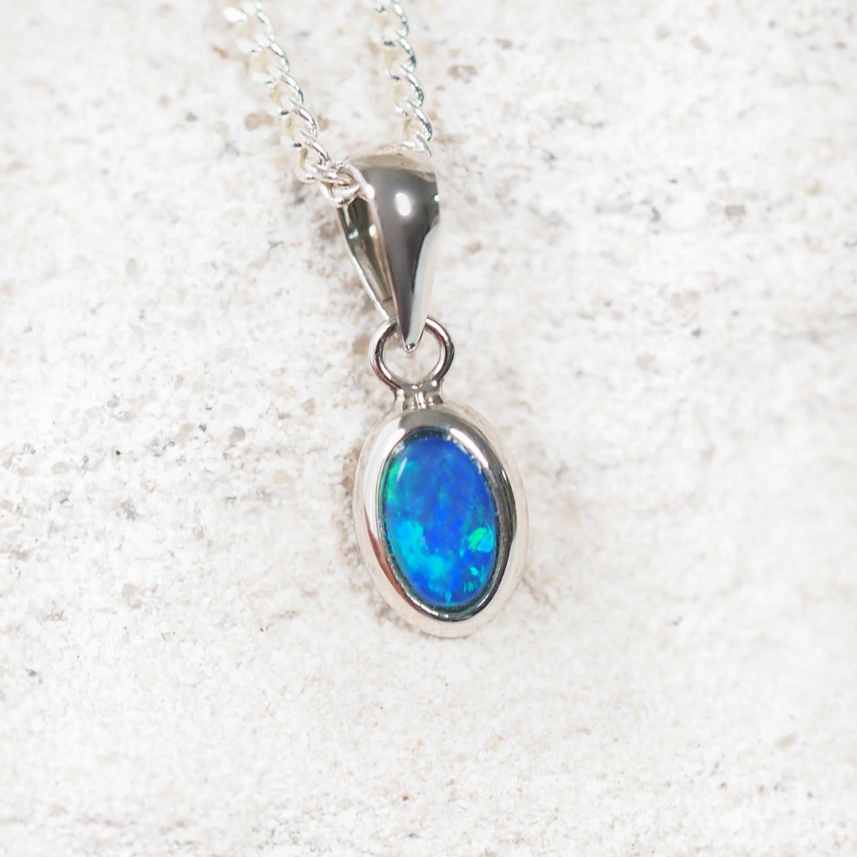 Sterling silver opal pendant necklace featuring an oval-shaped blue and green Australian doublet opal in a contemporary bezel setting.