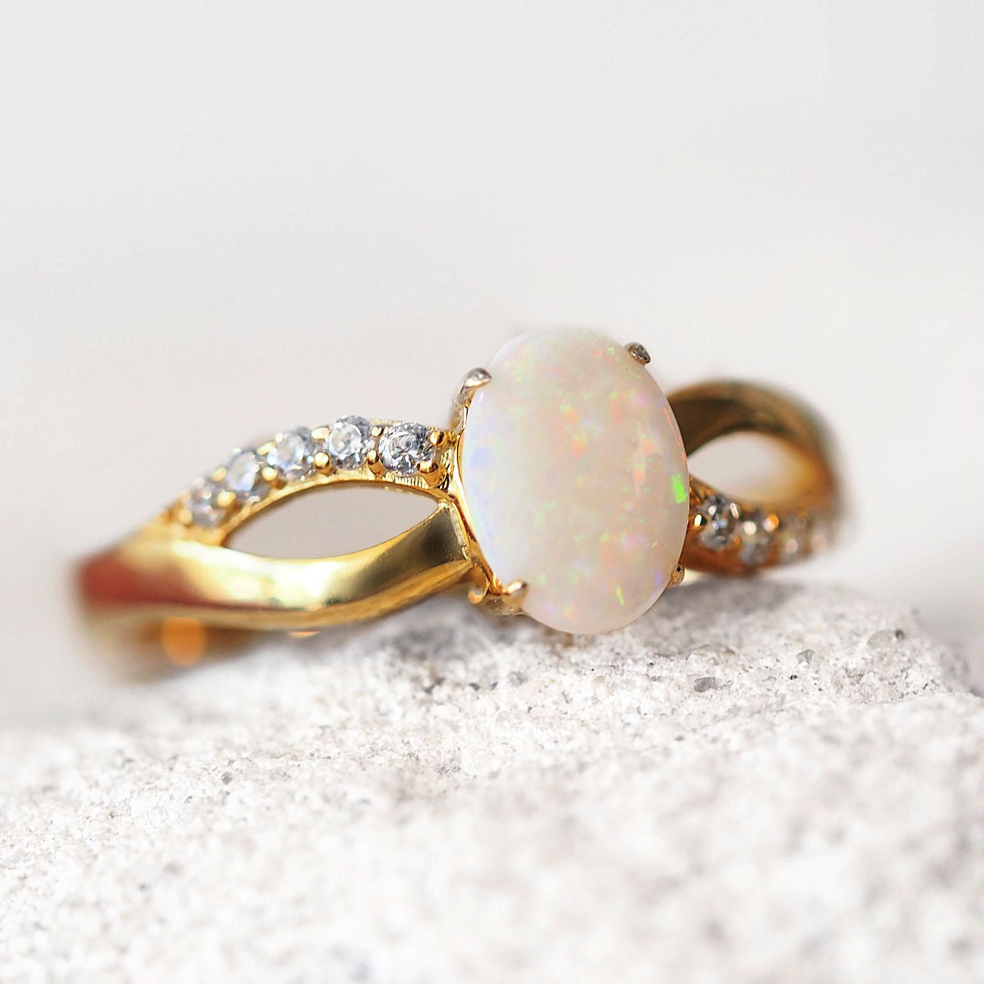Gold ring with an opal stone and small crystals on a textured surface