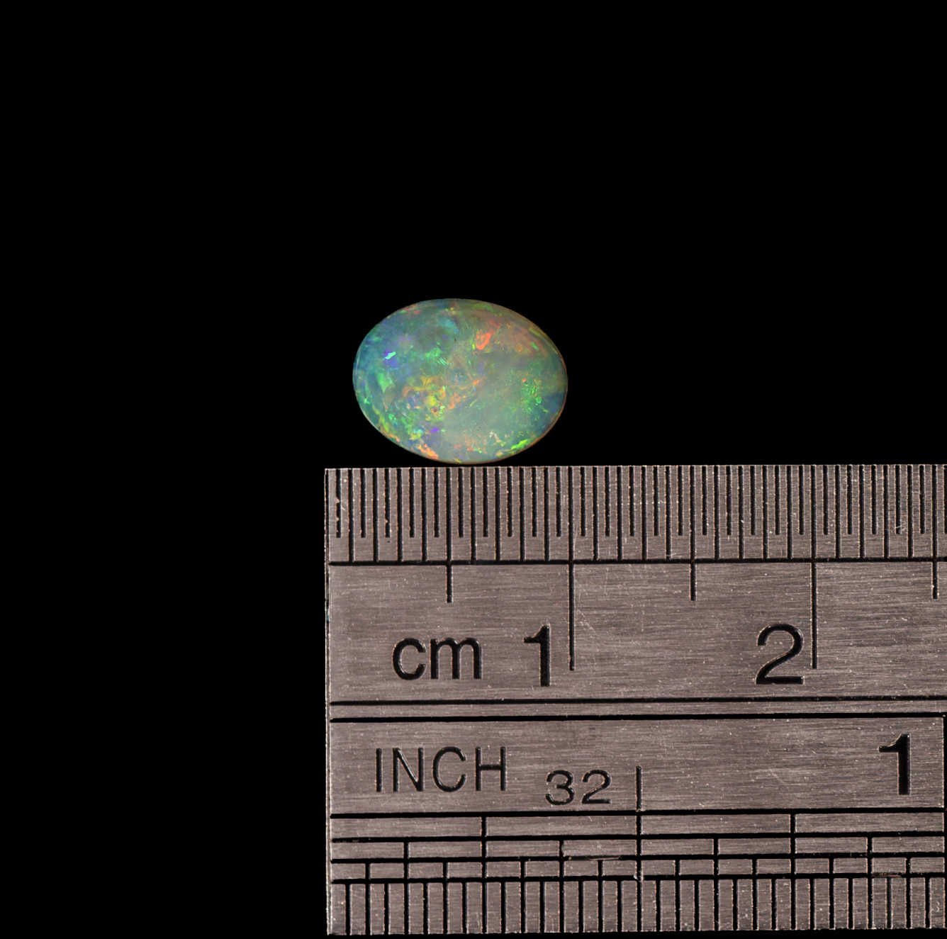 Opal stone with a ruler for scale on a black background