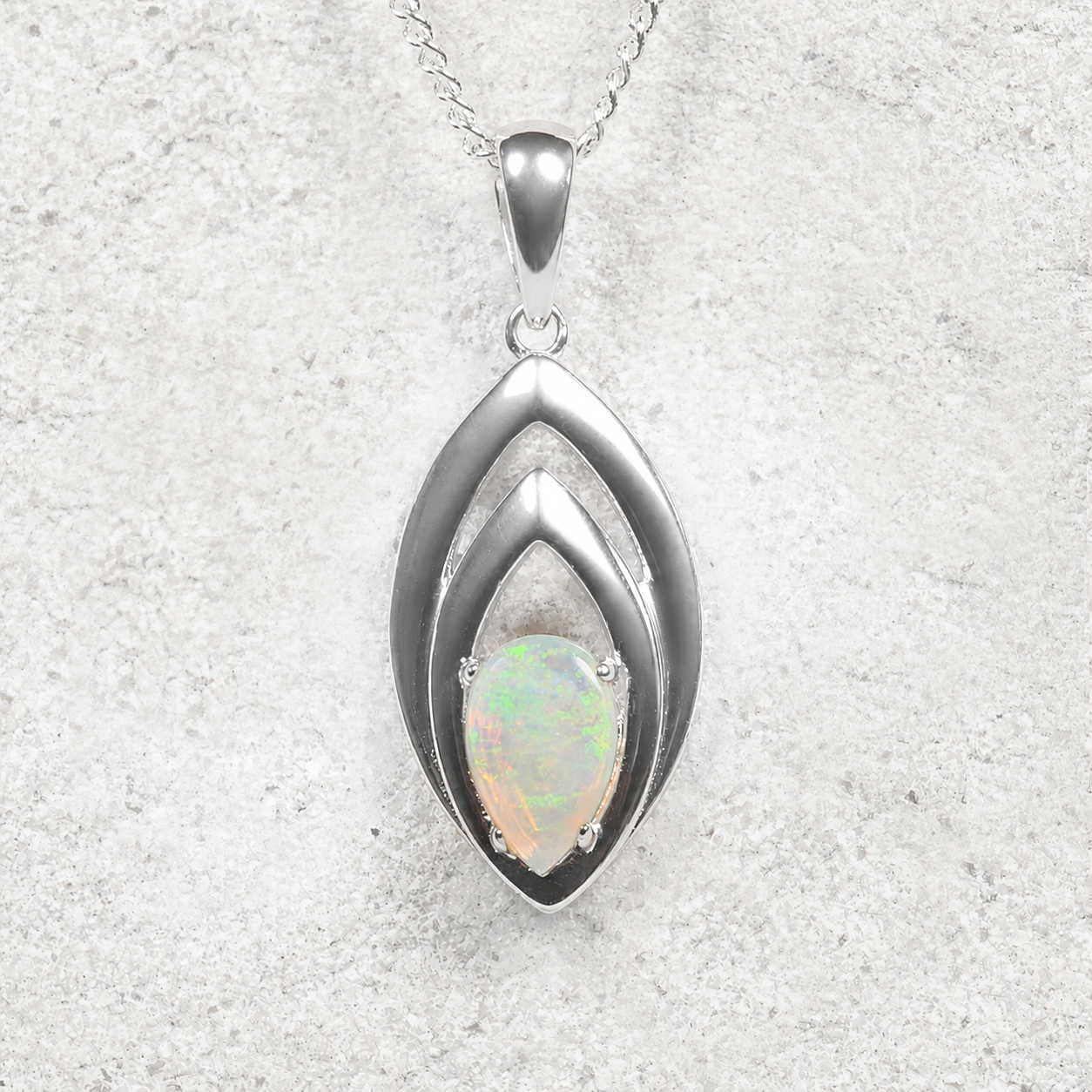 Silver pendant with opal stone on a textured gray background