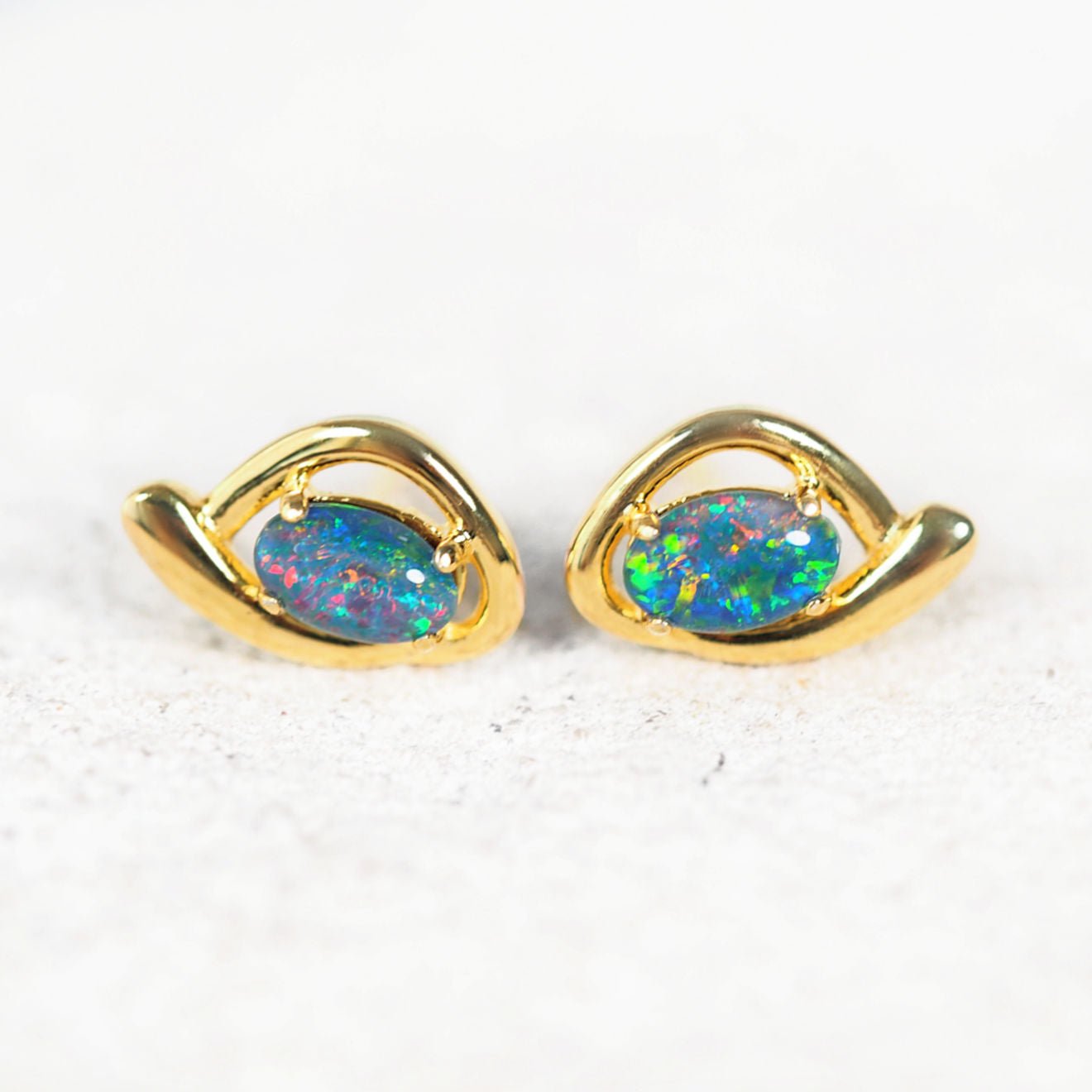 Pair of gold opal earrings on a white background