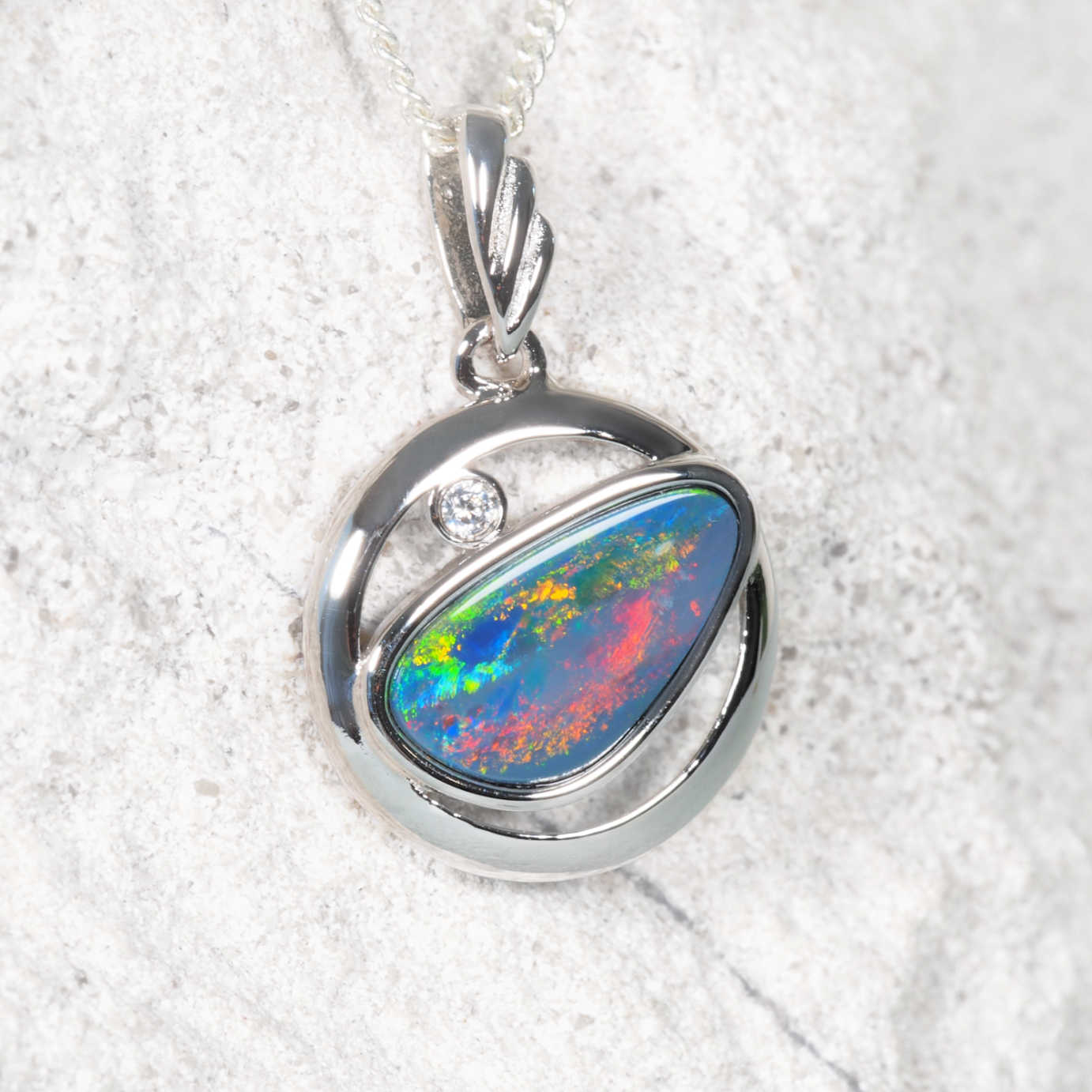Opal pendant with silver setting on a white background