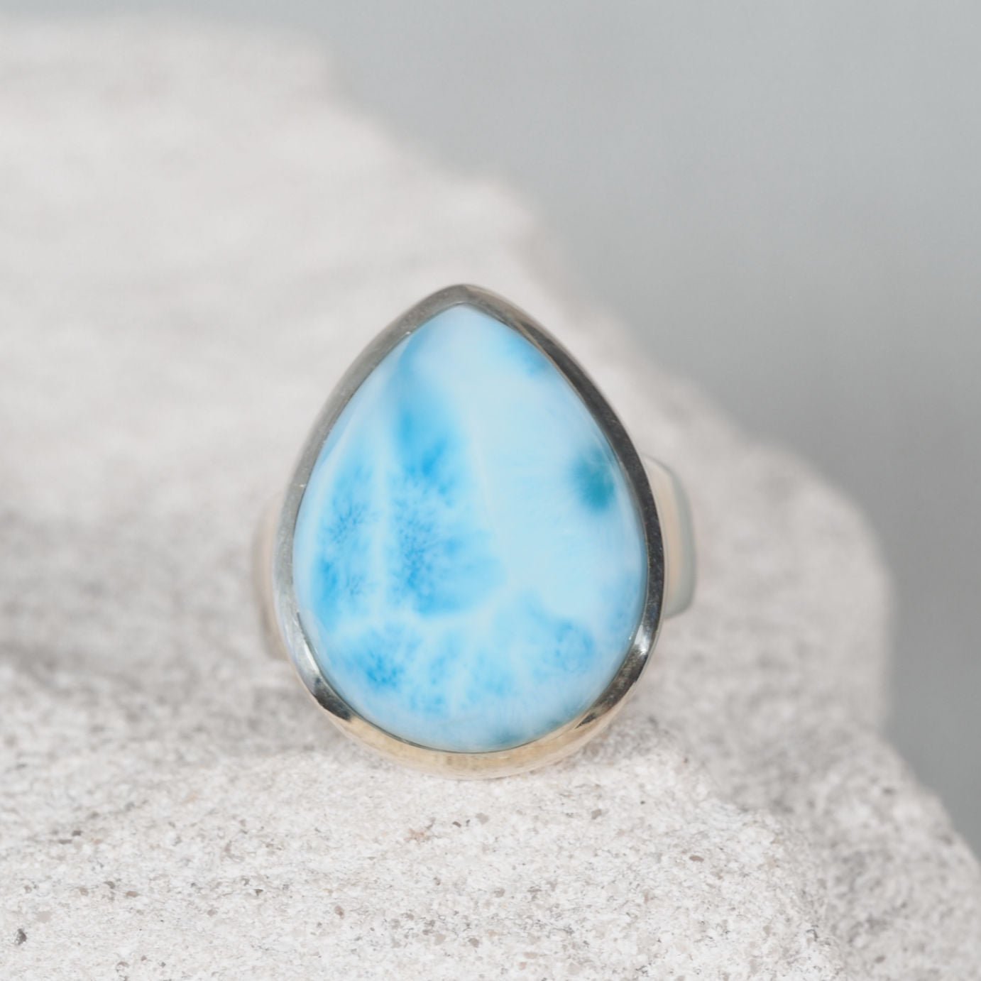 Teardrop Larimar ring in polished silver showcasing soft blue tones with gentle white patterns