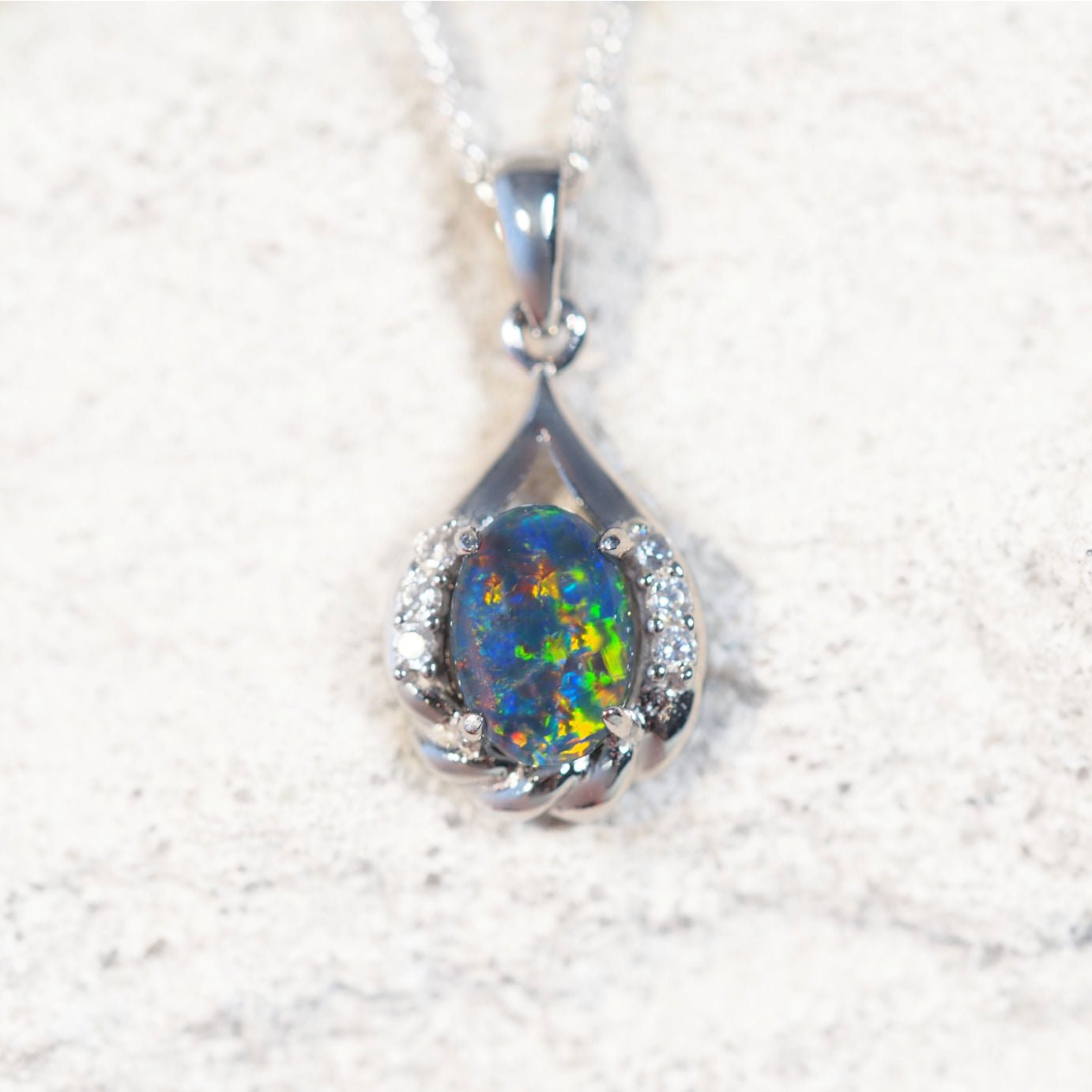 'Laina' opal pendant in sterling silver with claw-set oval Australian triplet opal in vibrant multi-coloured tones framed by six sparkling cubic zirconias