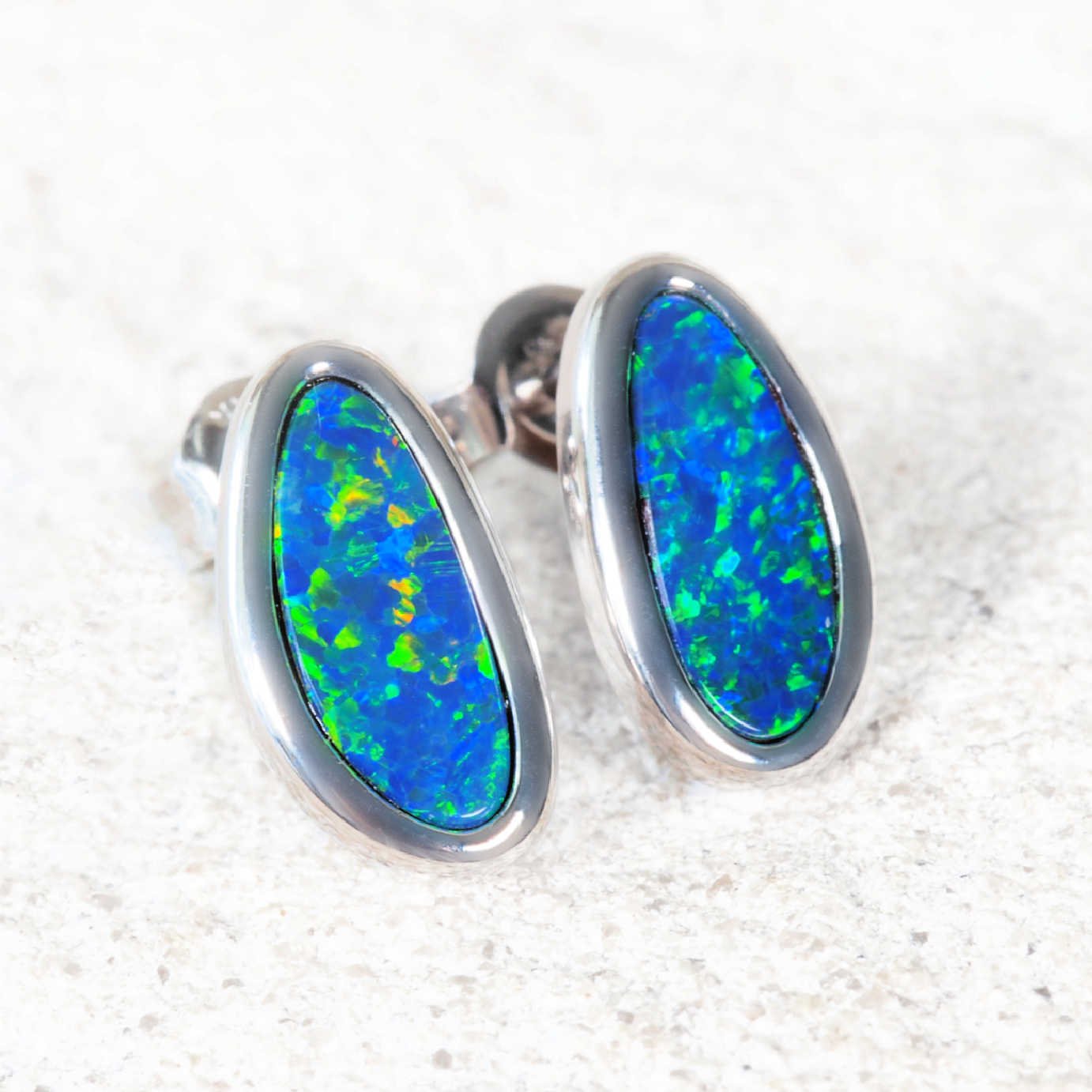 Opal earrings with white gold setting on a textured white background