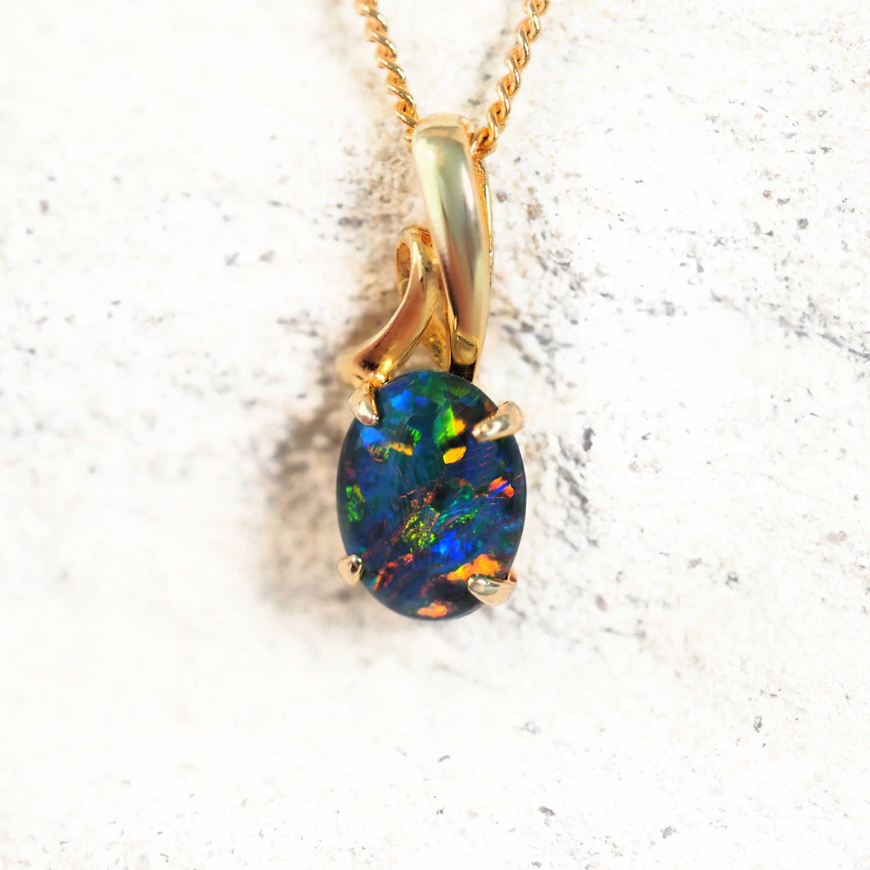 Gold-plated silver opal pendant necklace with claw-set multi-coloured Australian triplet opal in a decorative design, on matching chain.
