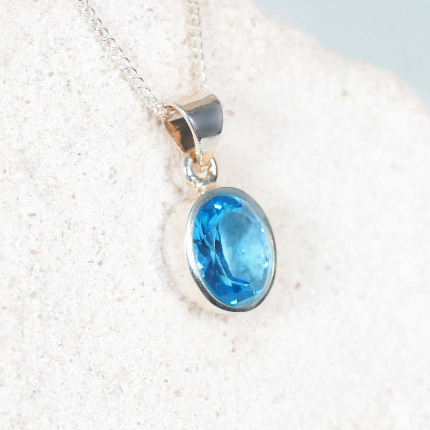 Close-up of the 'Lilli' pendant highlighting a small faceted Blue Topaz securely held in a sleek silver bezel setting