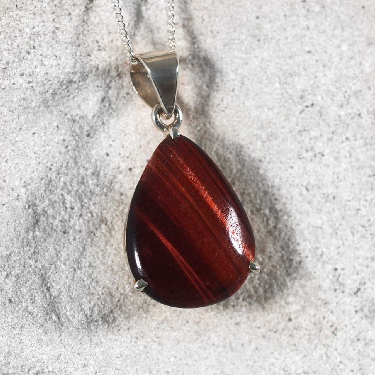 Close-up of Red Tiger Eye pendant showing rich reddish-brown hues and light reflections.