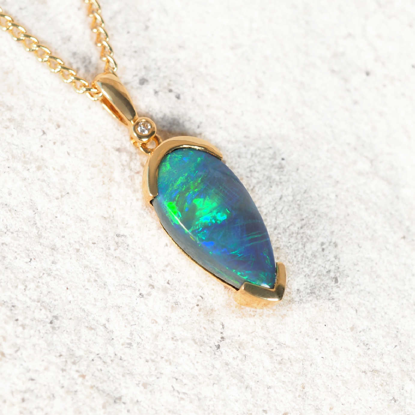 Elegant gold teardrop black opal necklace featuring vivid green and blue play-of-colour