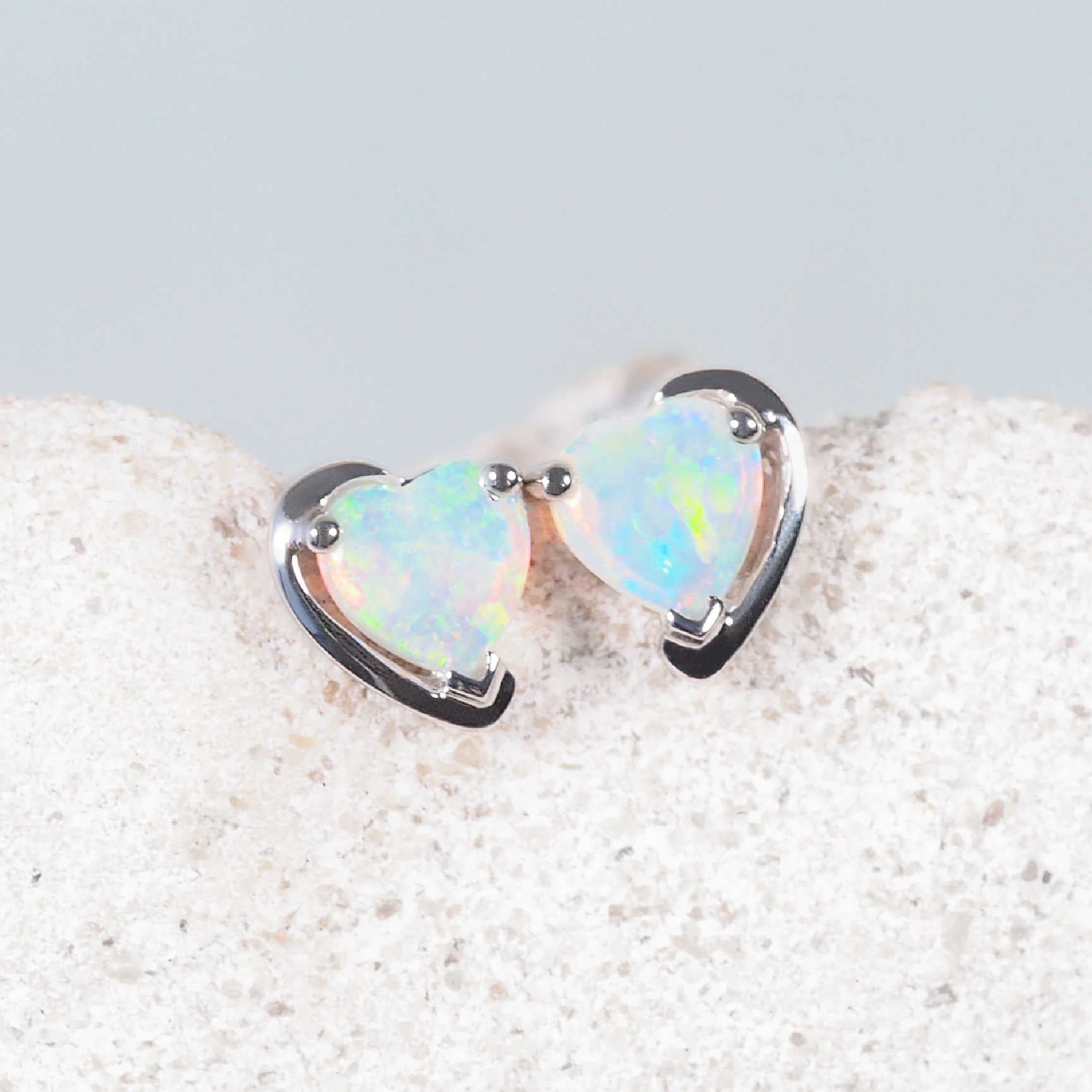 Close-up of 14ct white gold stud earrings with vibrant green, blue, and pink opals