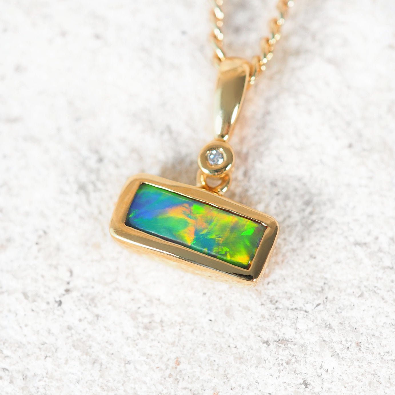Rectangular Lightning Ridge black opal pendant in 18ct yellow gold with diamond accent
