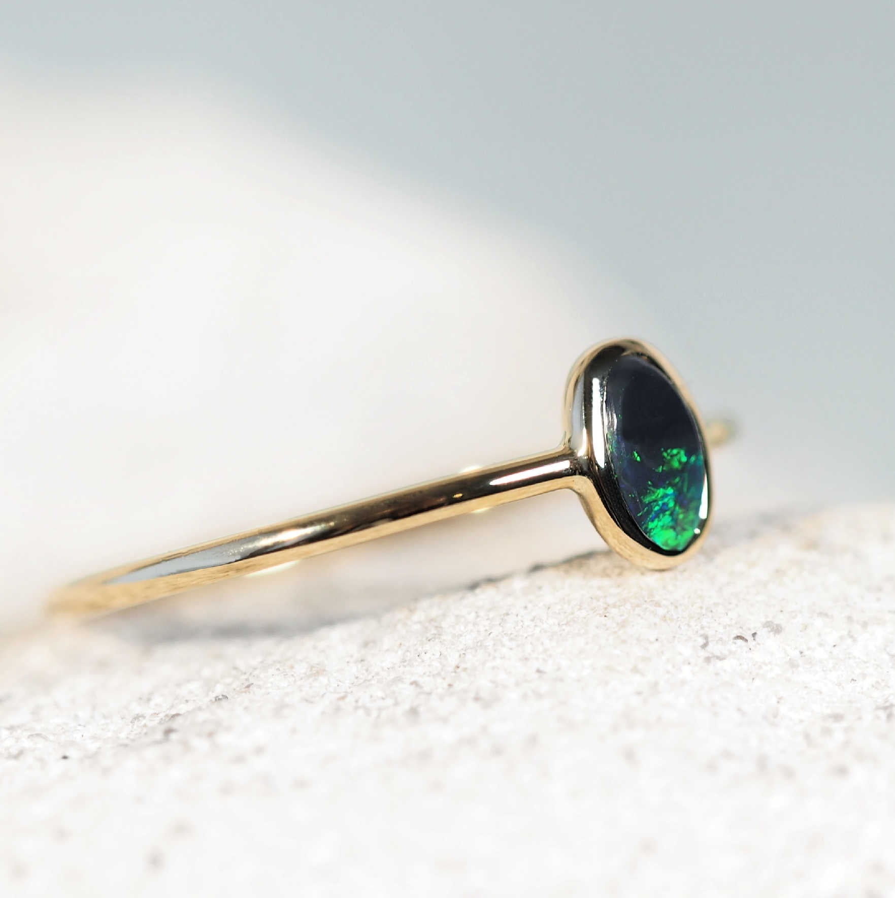 Stackable black opal ring showing green play-of-colour on finger
