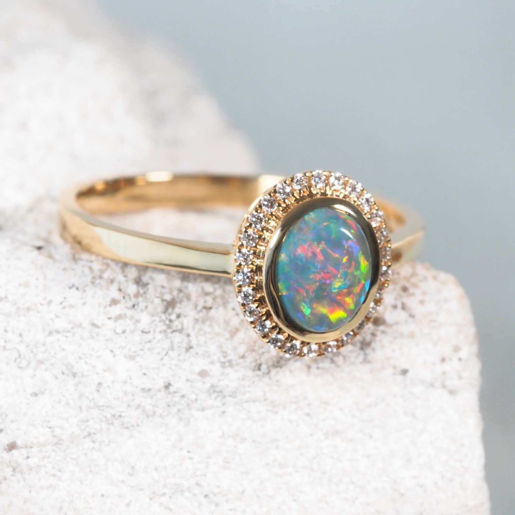 Side view of 'Mairi' gold ring showcasing round-oval black opal and sparkling diamond setting

