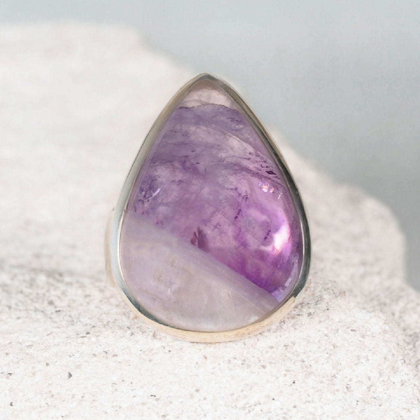 Elegant silver amethyst ring featuring a smooth teardrop amethyst cabochon with mostly light purple tones.