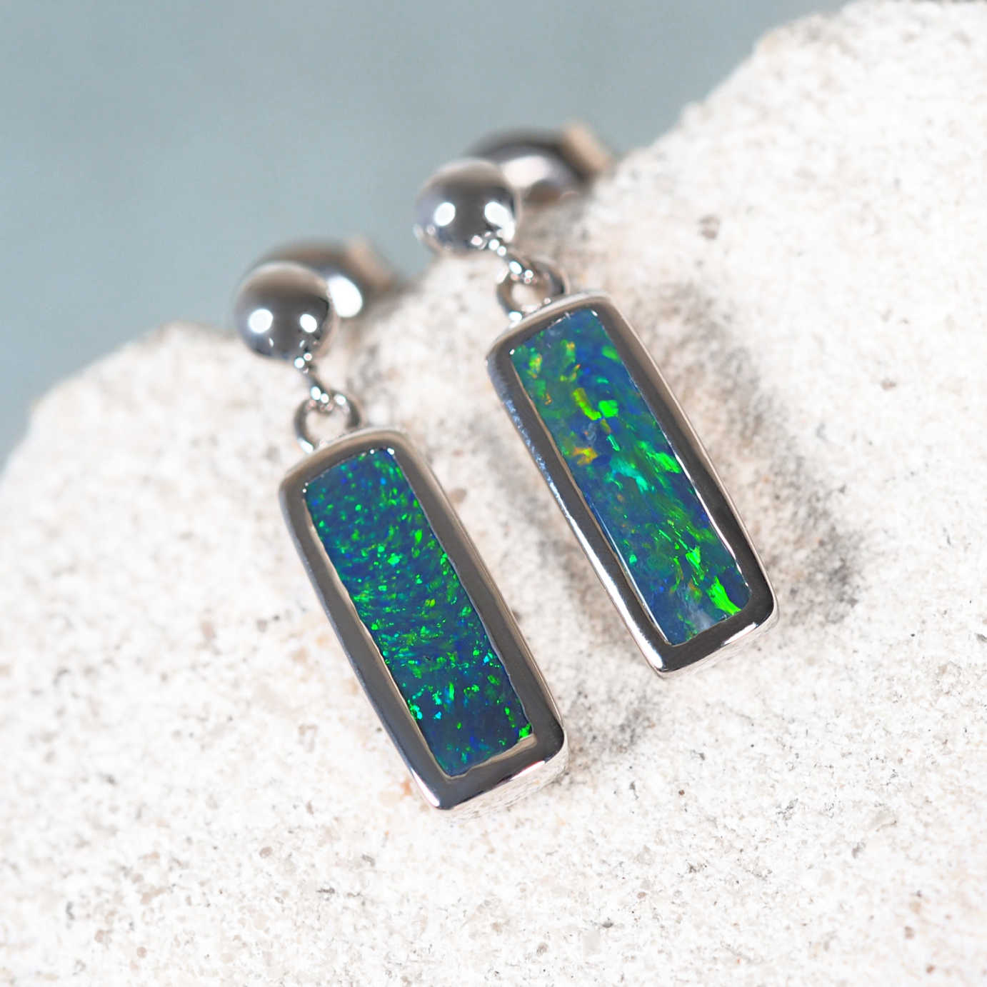 14ct white gold black opal drop earrings with flashes of red, green and blue