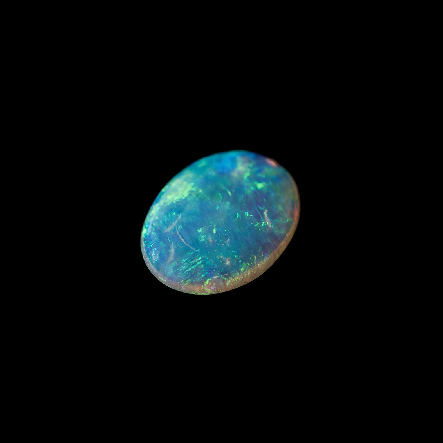 Opal stone with green play of light on a black background