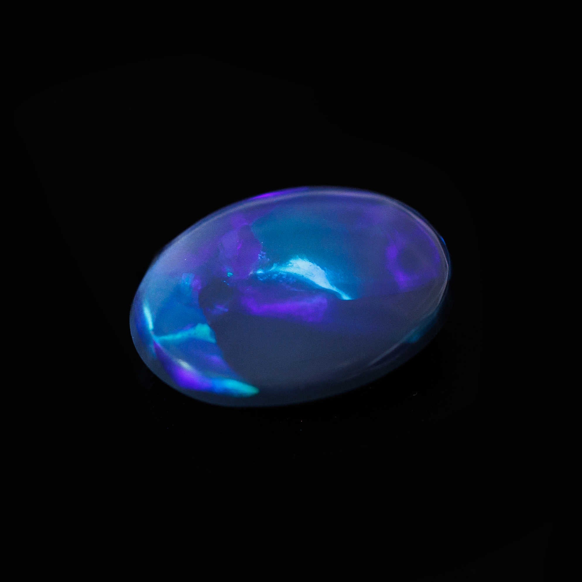 Close-up of oval-shaped Midnight Mirage opal showing intense colour play in a classic flagstone pattern
