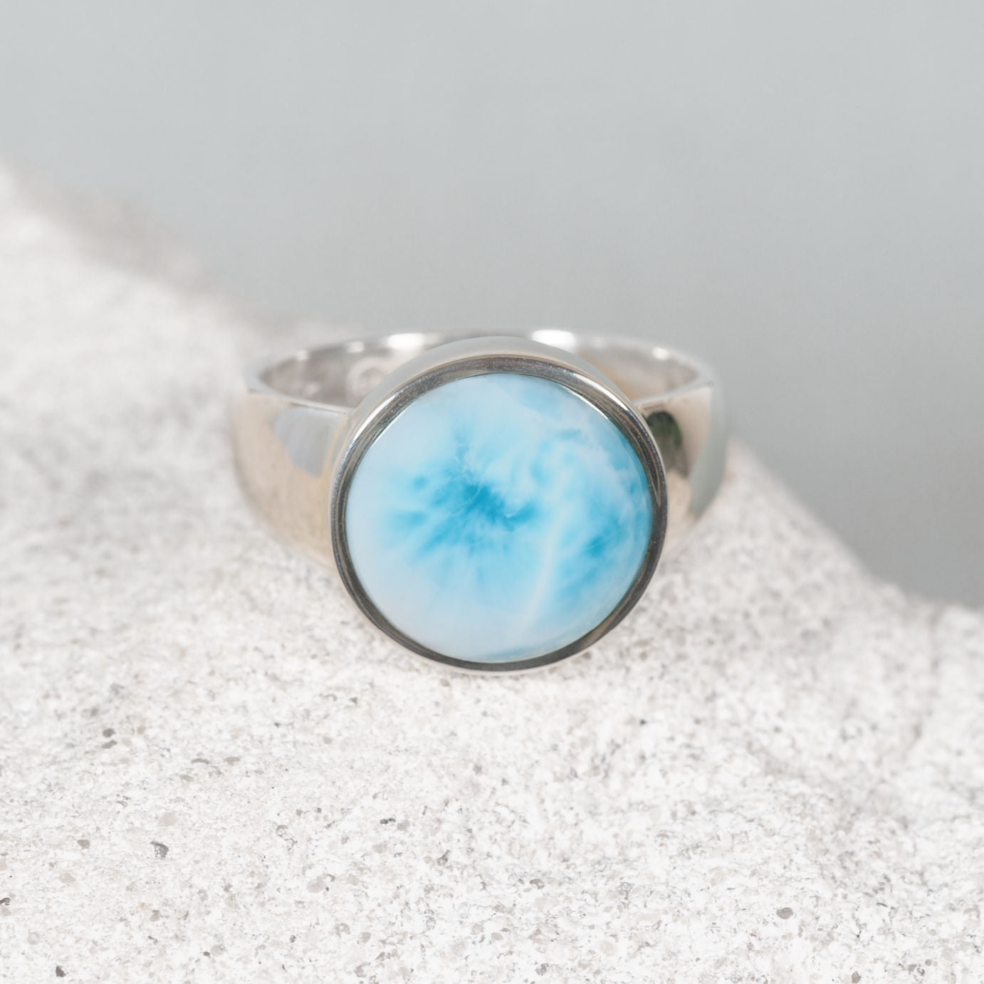Circular Larimar silver ring with a subtle off-center white line across a smooth blue cabochon