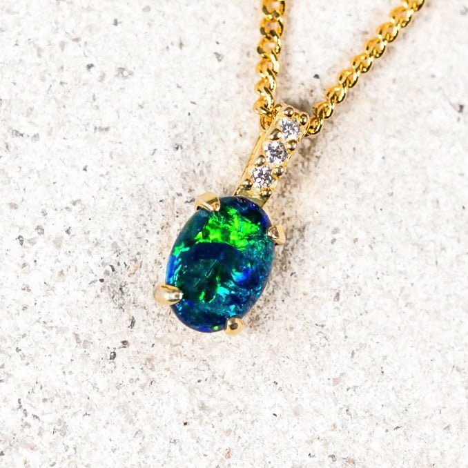 Elegant opal necklace featuring a blue-green oval triplet opal claw set in gold-plated silver with sparkling accents.