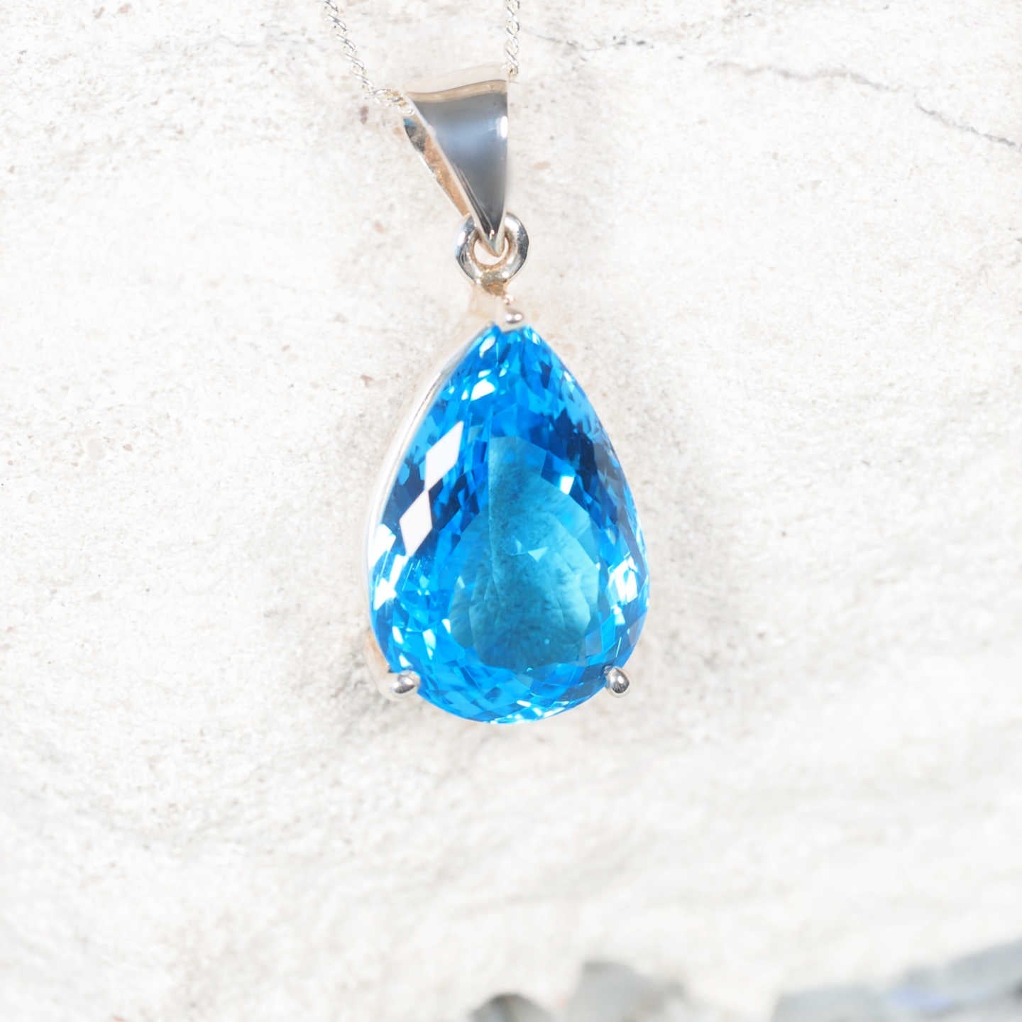 Close-up of the 'Moana' pendant highlighting faceted light Blue Topaz in a polished claw silver setting