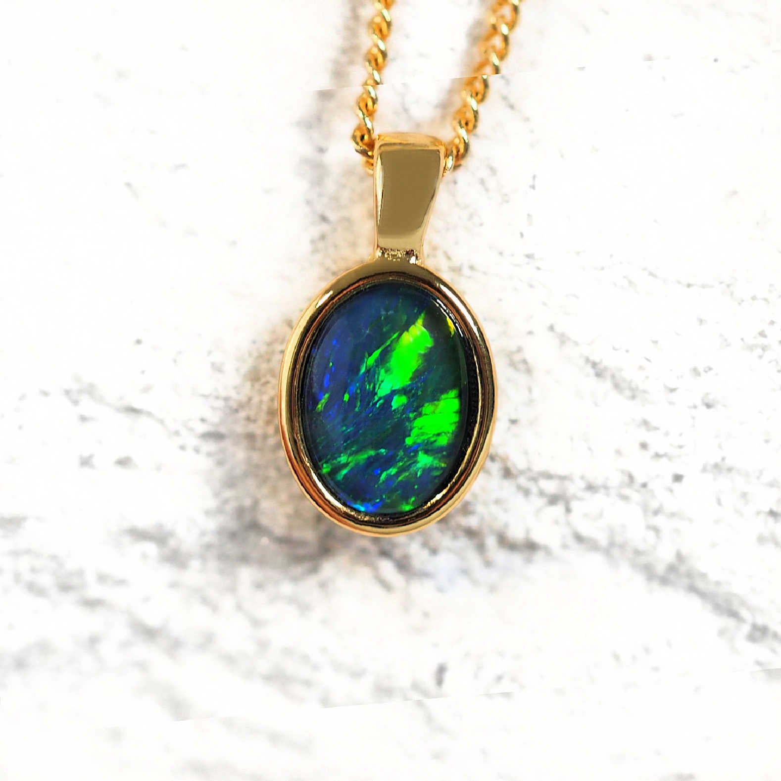 gold plated silver opal necklace bezel set with a blue and green-coloured, oval Australian triplet opal. 