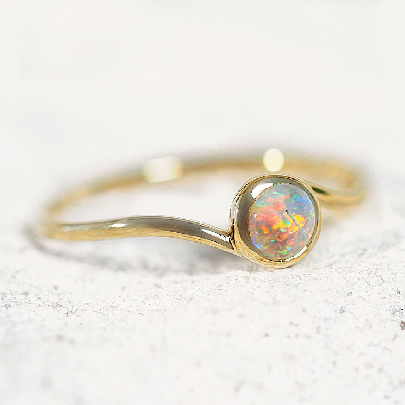 Gold ring with a colorful opal stone on a white background