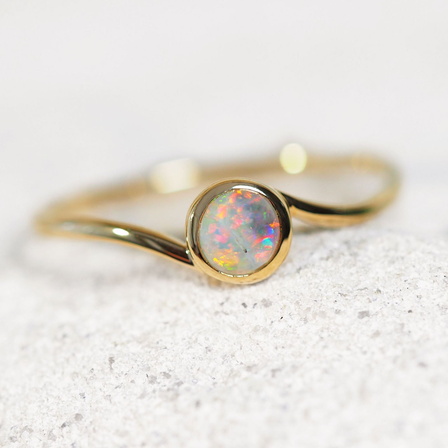 Gold ring with a opal stone on a light gray background