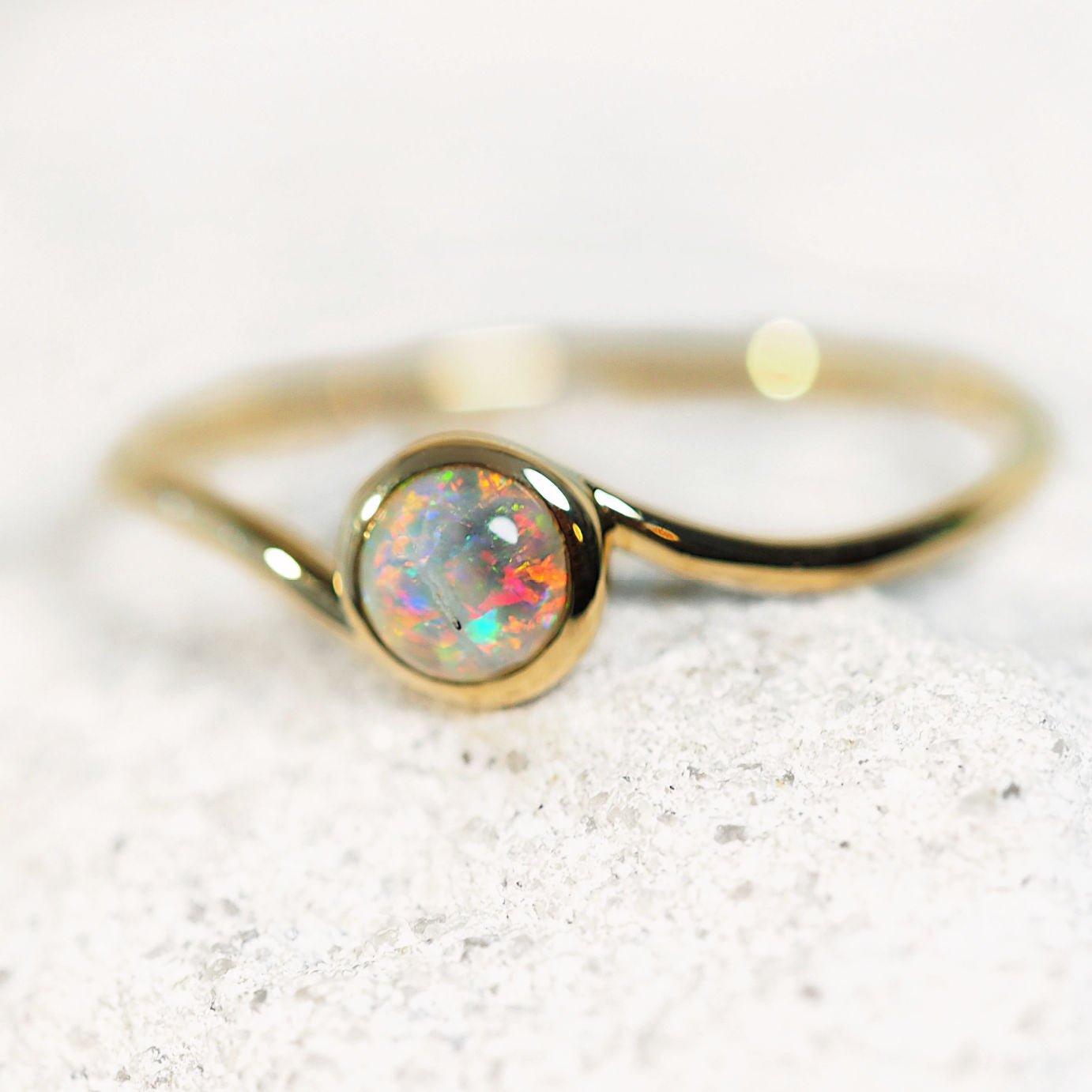 Gold ring with a Lightning Ridge opal stone on a white background