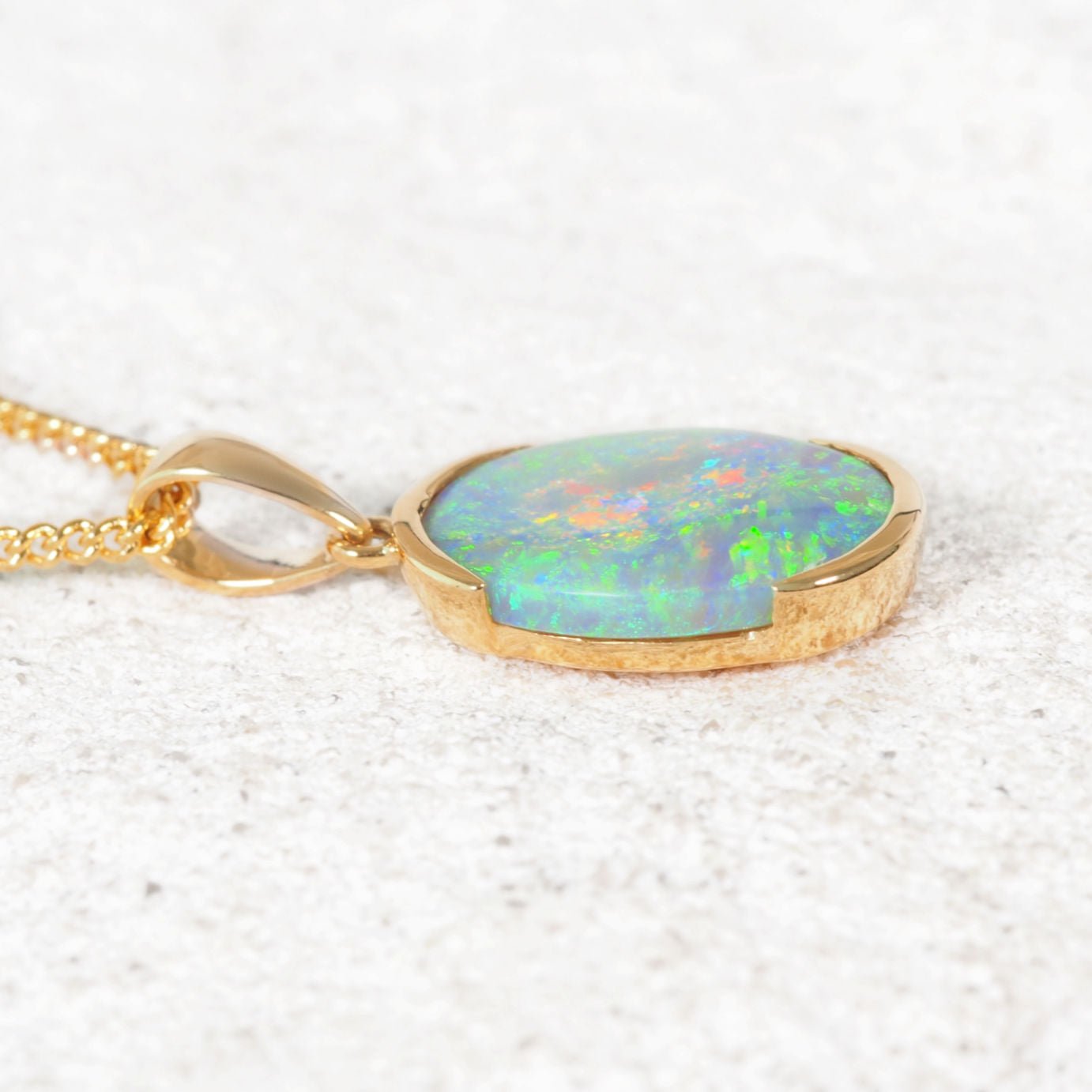 Lightning Ridge black opal pendant with gold setting on a rock 