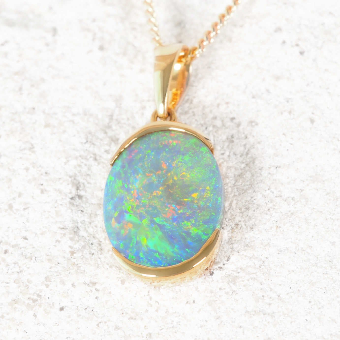 Gold black opal pendant necklace on a white background