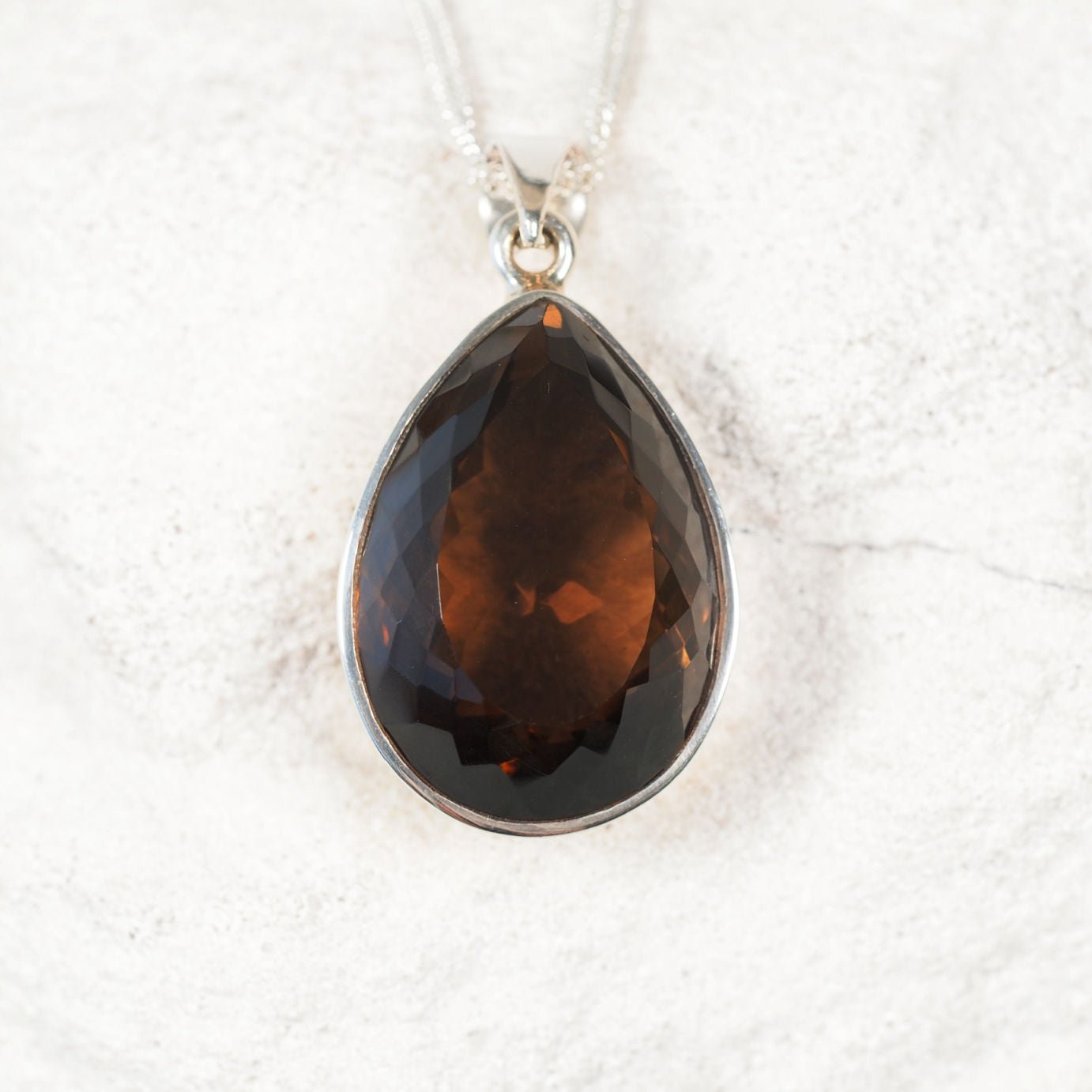 Faceted teardrop Smokey Quartz pendant set in a smooth silver bezel, highlighting warm brown tones