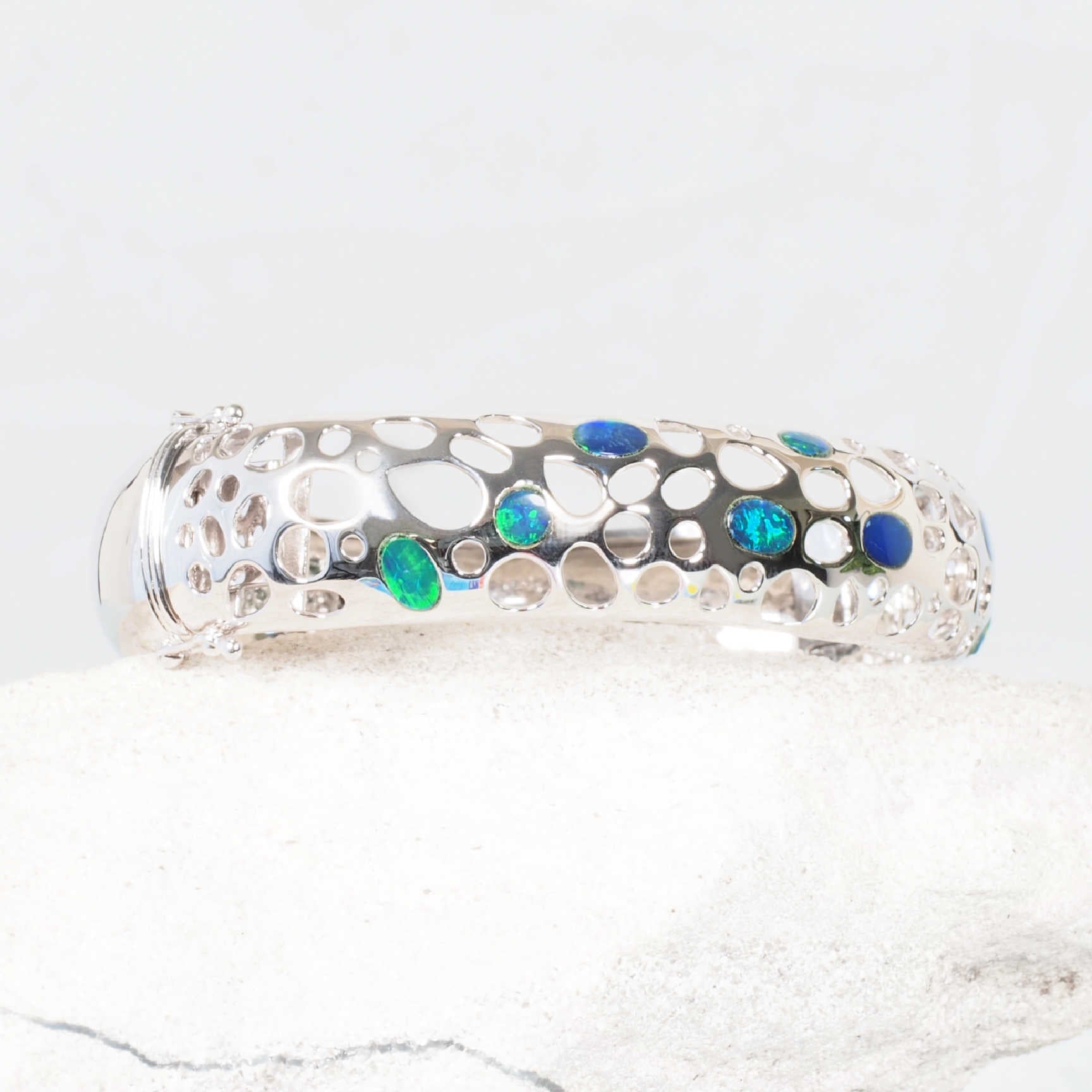 Modern hole-punch design silver bangle with vibrant oval opals – ‘Nova’