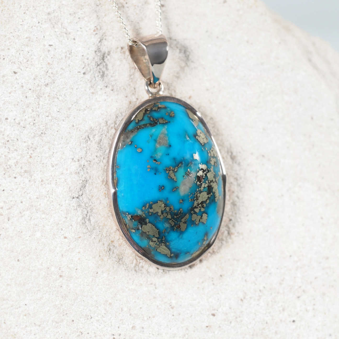 Elegant 'Nyra' pendant showcasing genuine Persian turquoise in a sleek silver setting, highlighting its natural beauty and charm.