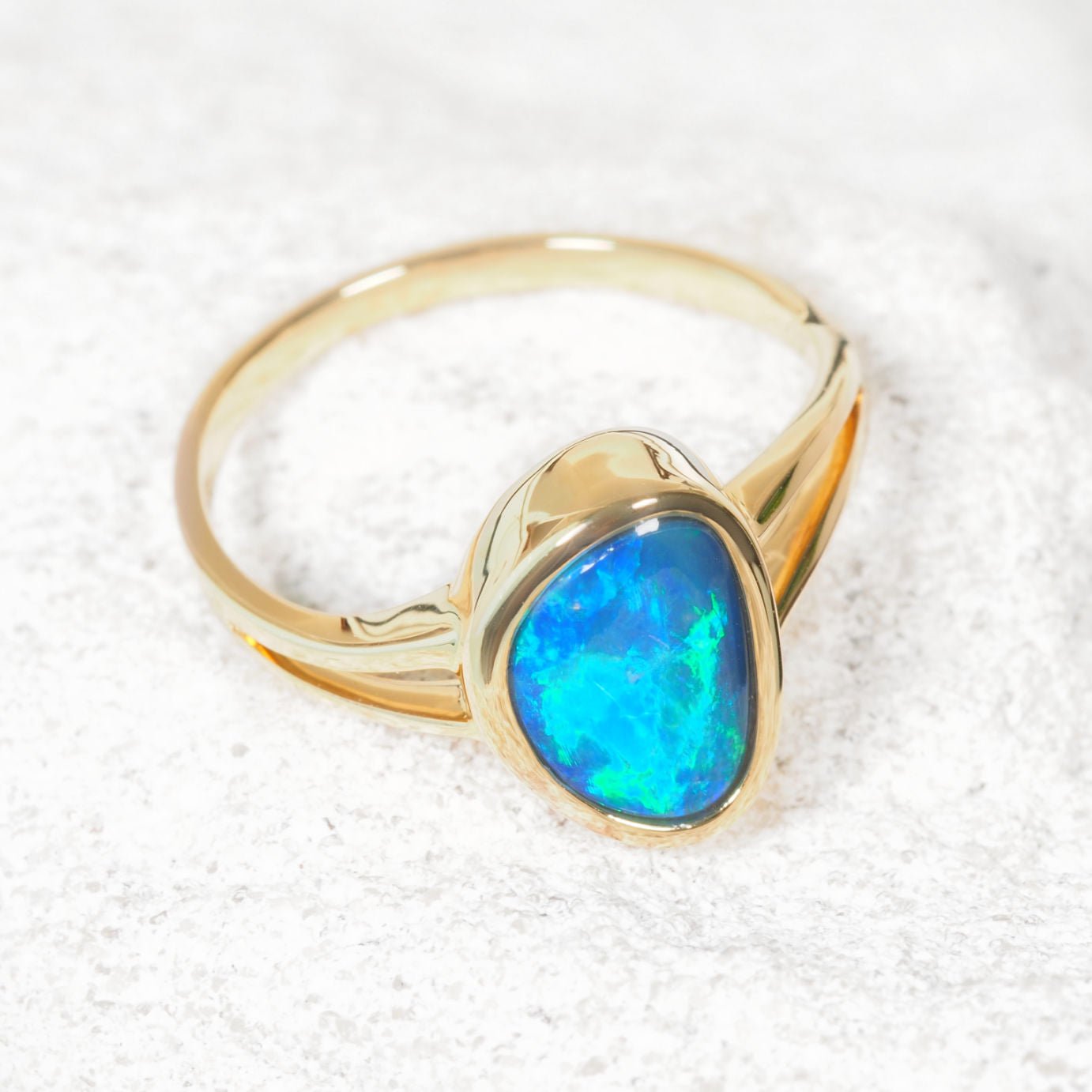 Gold ring with a blue opal stone on a white background