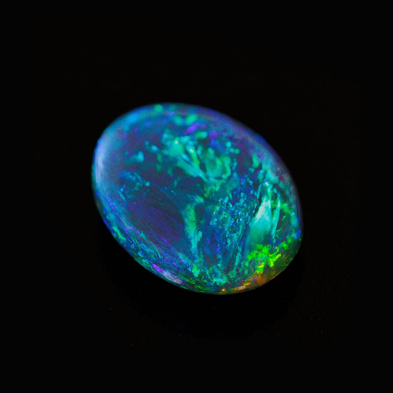 Oval-shaped solid black opal with peacock feather-like colour play