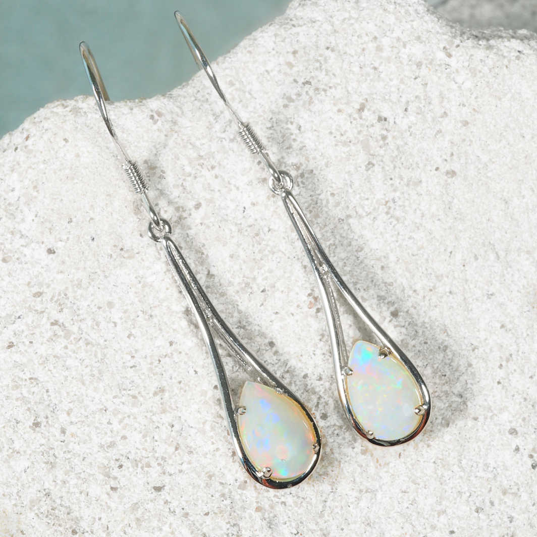 Opal earrings on a textured surface with a blurred natural background